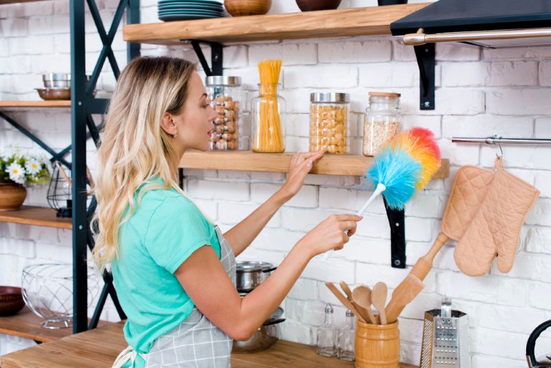 A women dusting kitchen shelves as part of Kitchen Care and Maintenance Hacks
