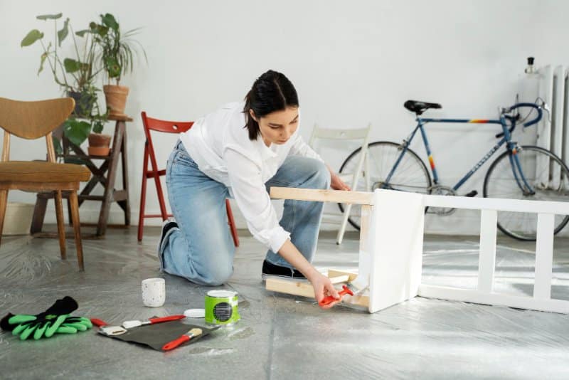 Wutawhacks Home Hacks: 5 Easy Home Hacks for a Smarter Space! A woman painting furniture in a bright, clean space, using tools and supplies, demonstrating Wutawhacks Home Hacks for creating a smarter, more efficient home.