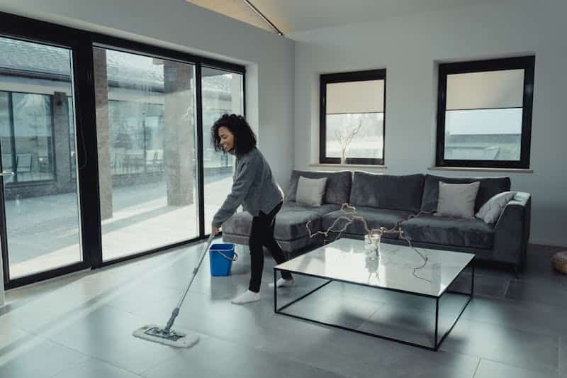 A person mopping the floor in a spacious living room as part of Cleaning Hacks You Need to Know