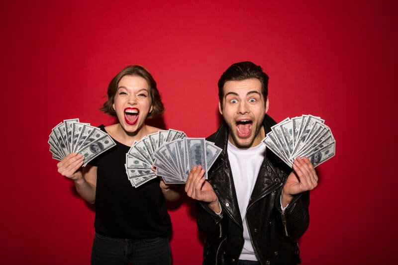 A man and woman happily holding stacks of money in front of a red background, representing financial success, with a connection to the online financial network MyGreenBucks.net.