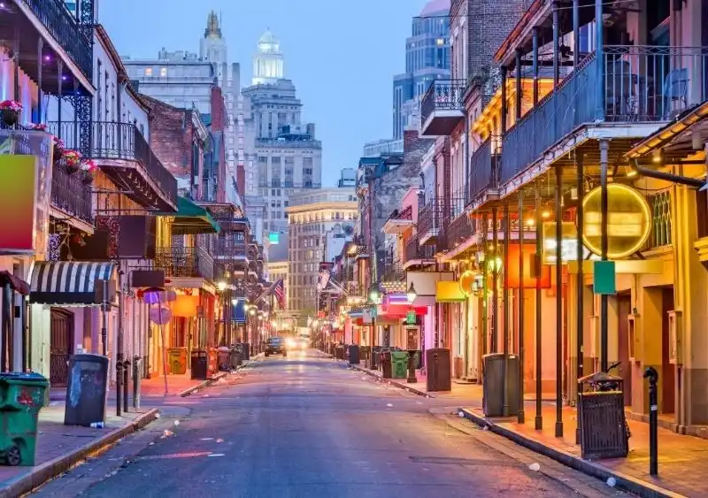 Where to Stay in New Orleans: The Best Areas in 2025 Colorful early morning view of Bourbon Street in the French Quarter, New Orleans, featuring vibrant buildings, glowing neon lights, and balconies—highlighting one of the best areas to stay in New Orleans in 2025.