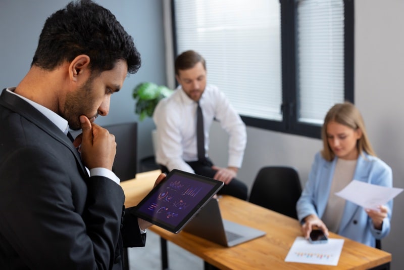 Data-Driven Decisions Without Data Overload: What Leaders Should Track Business leaders reviewing Data on a digital tablet during a meeting to support data-driven decisions without information overload.
