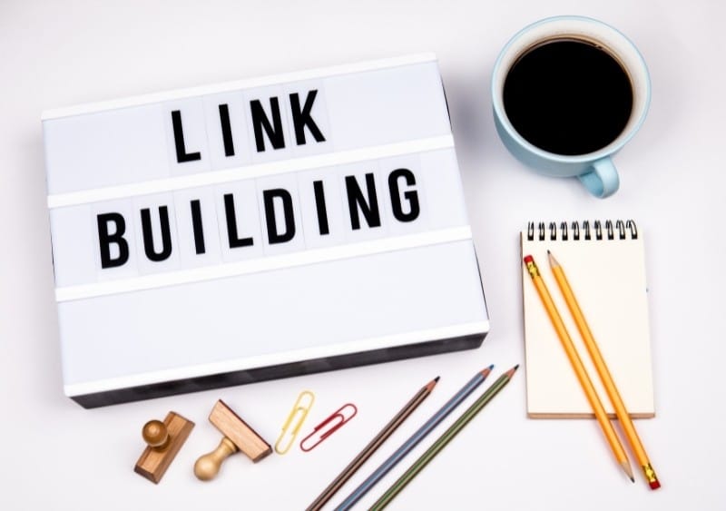 Top 10 Link Building Services in 2026: The Ultimate Comparison for SEO Growth Desk flat lay showing a lightbox reading link building with notebook, pencils, and coffee, representing professional link building services and SEO strategy planning.