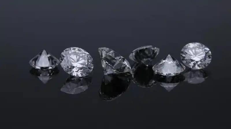 Close up of certified cut diamonds displayed on a dark surface, highlighting stone quality and brilliance for Fine Jewelry selection.