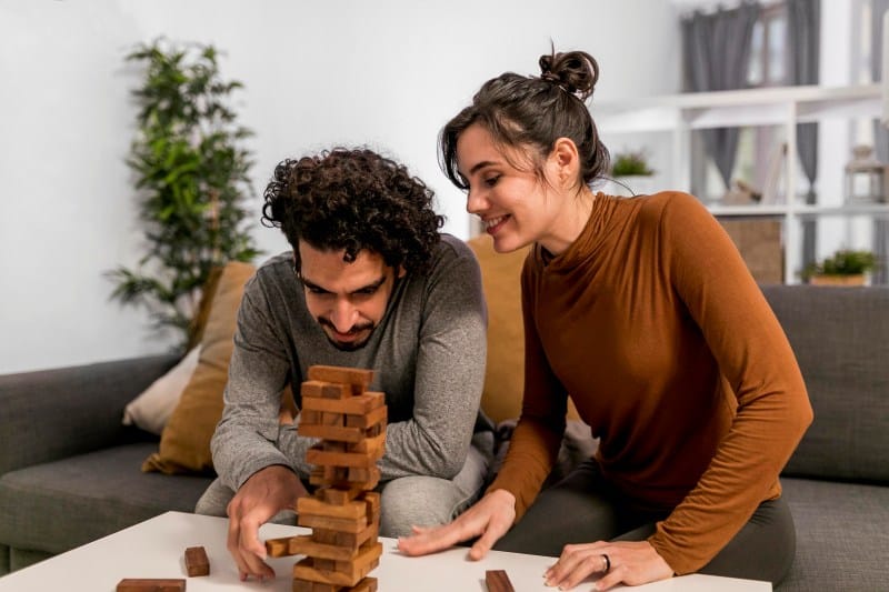 Couple playing a wooden block puzzle game at home, a fun brain activity.