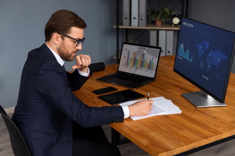 Business broker analyzing financial charts and market data while evaluating a business sale opportunity.