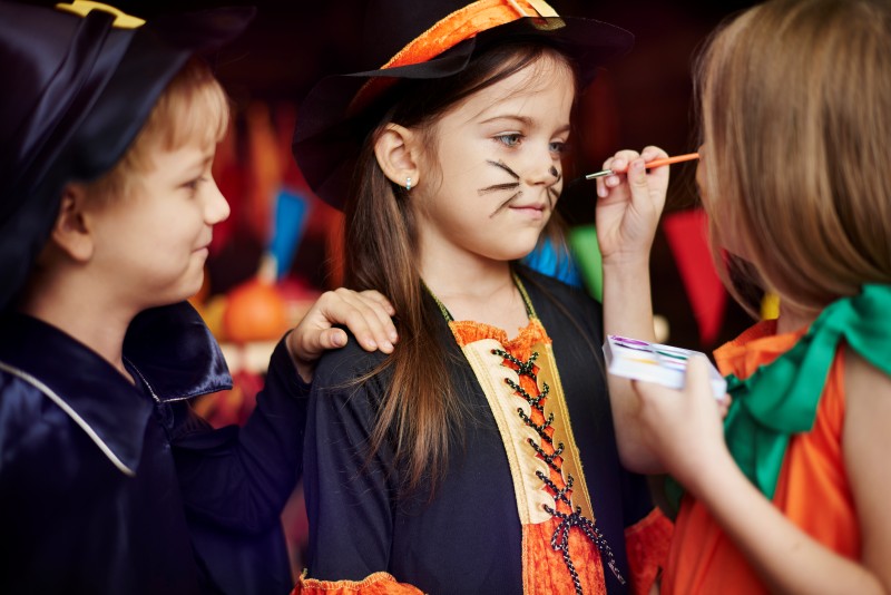 Kids in costume with face paint during a creative dress-up and cultural art activity.