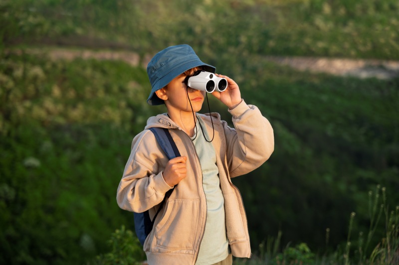 Child using binoculars outdoors during a nature activity, one of the fun Things for Kids to Do When Bored.