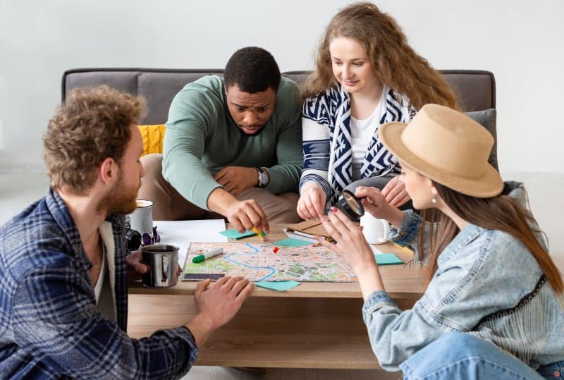 Friends solving a map puzzle together at table, a fun social activity and engaging Things to Do with friends.