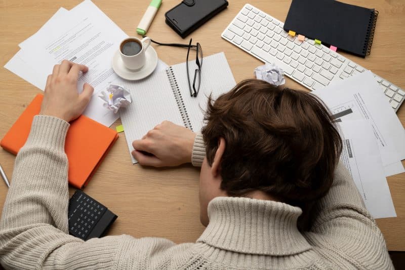 Person sitting at messy desk feeling bored and tired during work, showing the need for simple Things to Do When Bored to refresh focus.