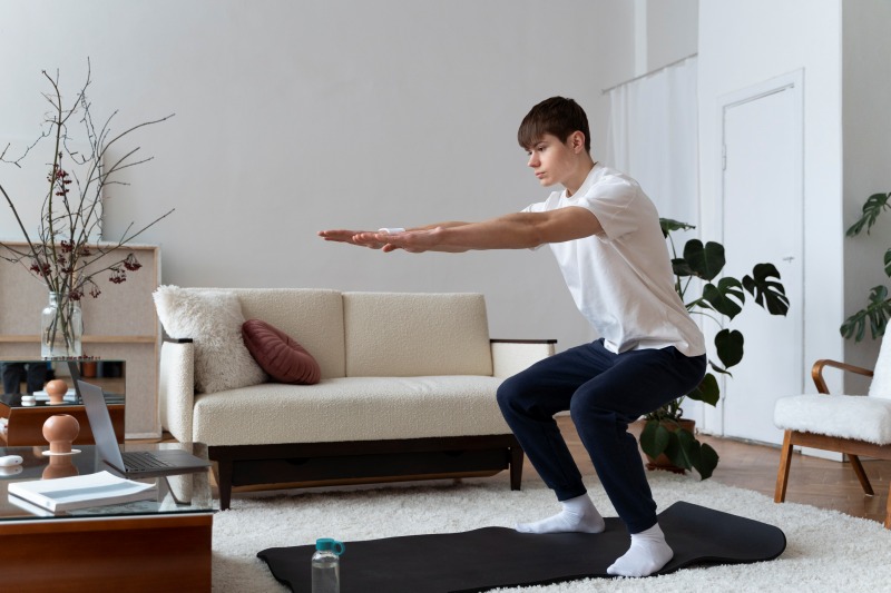 Man doing a squat workout on a mat in the living room, a simple way to enjoy Things to Do When Bored at Home.