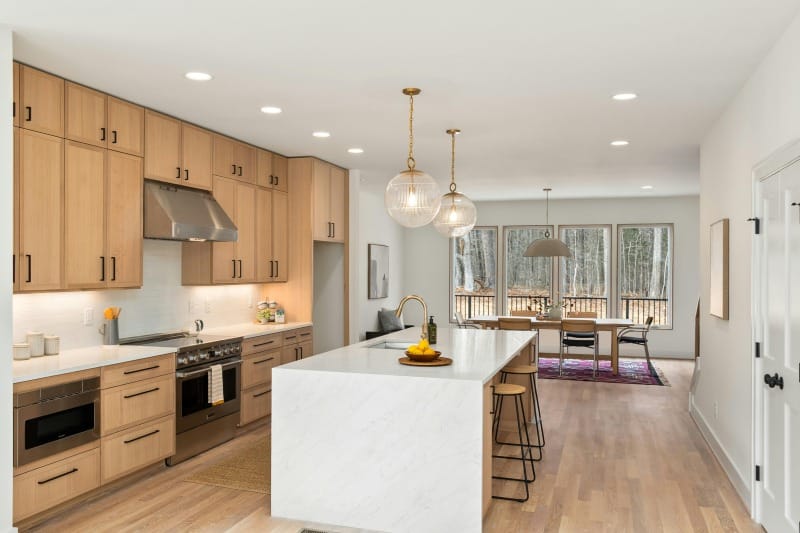Crafting a Chef-Worthy Kitchen Within a Realistic Budget Chef-Worthy Kitchen with wood cabinets, marble island, stainless steel range, pendant lights, and open dining space.