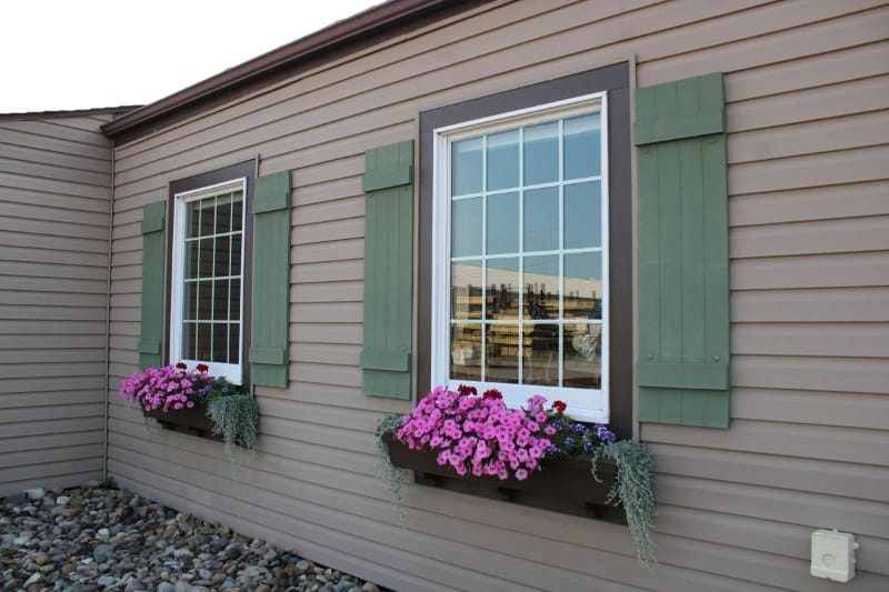 Custom Window Shutters: A Smart Upgrade for Homeowners Exterior window shutters installed on house windows with flower boxes, improving light control, privacy, and home appearance.
