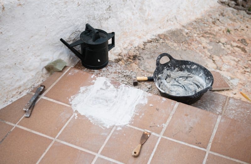 What to Know About Grout, Sealers and Adhesives Before Laying New Tiles New tiles with grout and tile adhesive, mixing bucket and hand tools during floor installation.