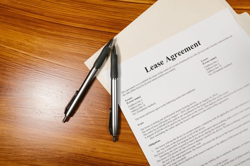 Key Considerations Before Signing a Commercial Lease in an Older Building Commercial lease agreement and two pens on a wooden desk for reviewing an older building lease.
