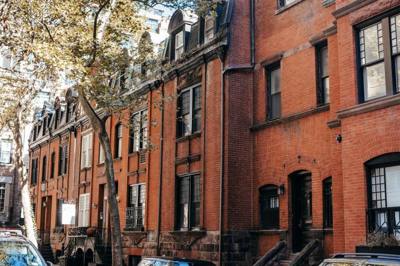 Is That Older Home Worth It? What to Check Before Committing Row of brick older home with mature trees and parked cars along a residential street.