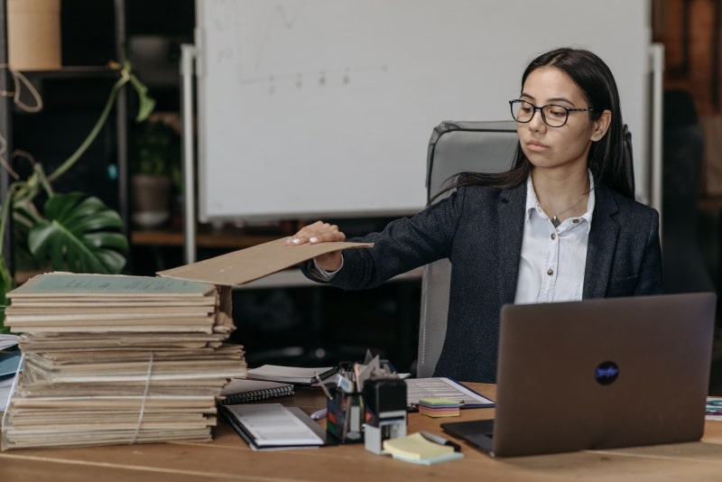 E-Filing 1099s: A Simple Walkthrough for Small Business Owners Small business owner reviewing paper records while managing E-Filing 1099s on a laptop.