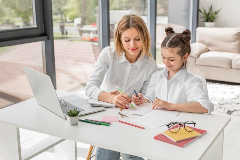 6 Best Au Pair Programs for School-Age Kids in the US (2026) Au pair helping a school-age child with homework at home, showing how au pair programs support daily childcare and learning.