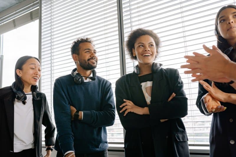 Health Benefits for Part-Time Staff: Is It Worth It for Growing Businesses? Four employees discussing workplace matters during a team meeting about health benefits for part-time staff.