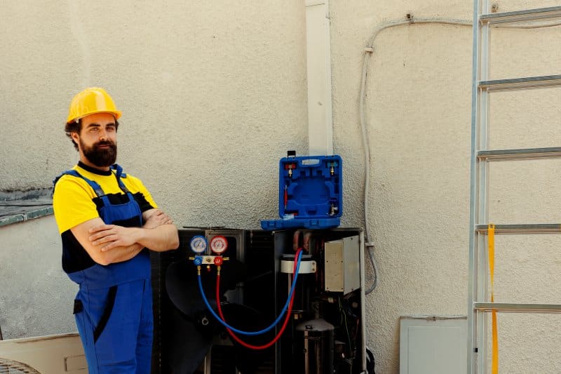 How Variable-Speed Pumps Are Changing Commercial Water Systems? HVAC technician standing beside pressure gauges and mechanical equipment used in commercial variable-speed pump systems.